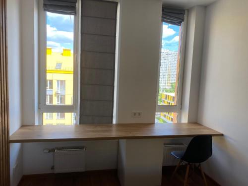 a wooden desk in a room with two windows at Comfort Town in Kyiv