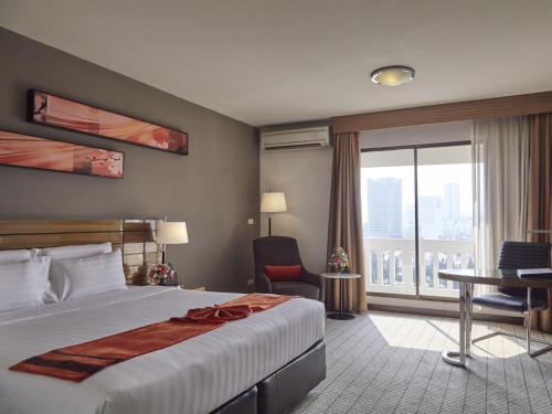 バンコクにあるメイプル ホテルのベッド、デスク、窓が備わるホテルルームです。