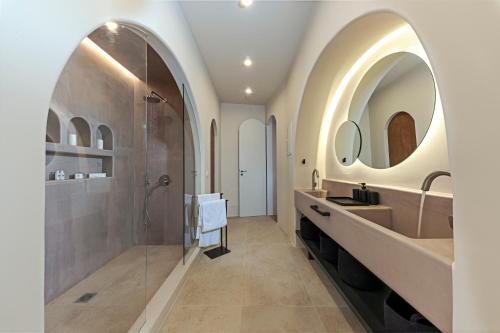 a bathroom with two sinks and a shower with two mirrors at Ambeli Sunset Villas in Megalochori