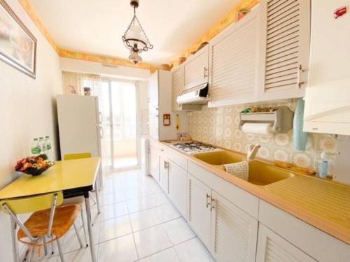 - une cuisine avec des placards blancs, une table et un réfrigérateur dans l'établissement Appartement au calme proche du centre-ville, à Sanary-sur-Mer