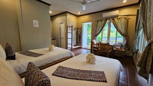 une chambre d'hôtel avec deux lits et une salle à manger dans l'établissement Bearlinbungalow, à Vang Vieng