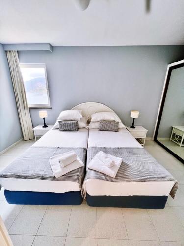 a bedroom with two beds and two lamps and a mirror at Atlantic Gardens Beach - atlanticgardensbeach com in Funchal
