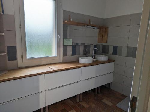 un bagno con due lavandini e una finestra di La Fontaine a Montgaillard-Lauragais