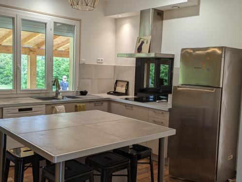 a kitchen with a table and a stainless steel refrigerator at La Fontaine in Montgaillard-Lauragais