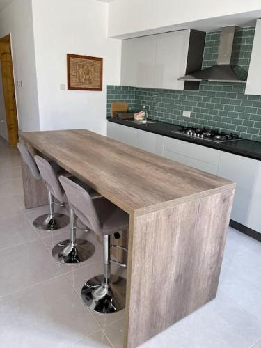 a kitchen with a wooden table and some chairs at Sunset Apt Modern 1 bedroom Apt near the Beach in Birżebbuġa