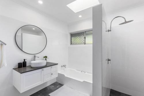 a white bathroom with a sink and a mirror at Stylish Home in Fig Tree Pocket near Lone Pine in Brisbane