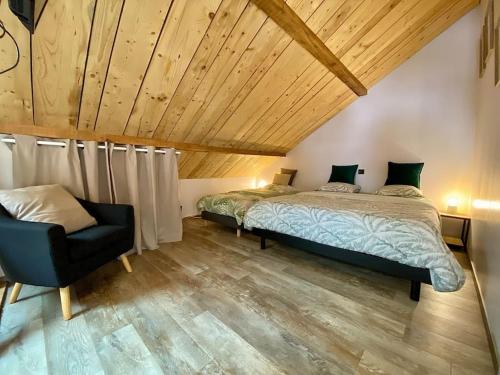 een slaapkamer met 2 bedden en een stoel bij Au Cocon du Haut Pergé in Gérardmer