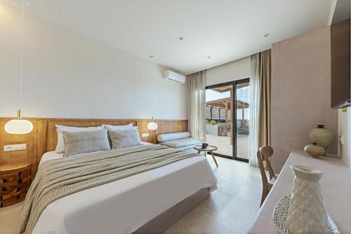 a bedroom with a large bed with a table and a chair at Ambeli Sunset Villas in Megalokhori
