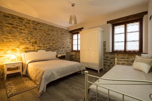 a bedroom with two beds and a brick wall at Appartamenti Gli Ippocastani in San Benedetto Belbo