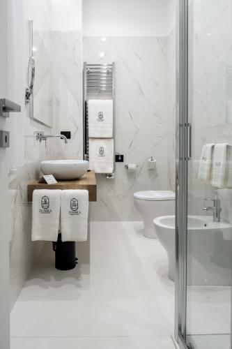 a white bathroom with a sink and a toilet at Domea Superior Rooms Bed and Breakfast in Reggio Calabria