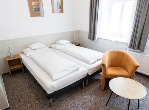 a hotel room with two beds and a chair at Hotel Beskid in Bielsko-Biała