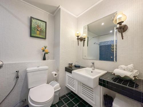 a bathroom with a sink and a toilet and a mirror at At Pingnakorn Nimman Hotel in Chiang Mai