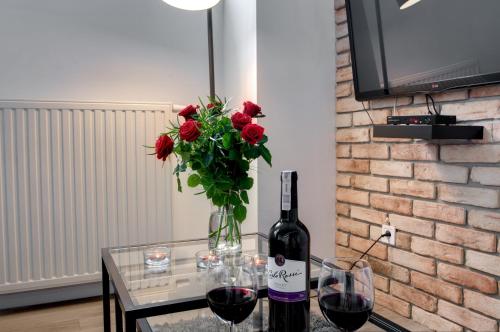 un tavolo di vetro con una bottiglia di vino e un vaso di rose rosse di Apartament Romantyczny Zamkowa15 a Cracovia