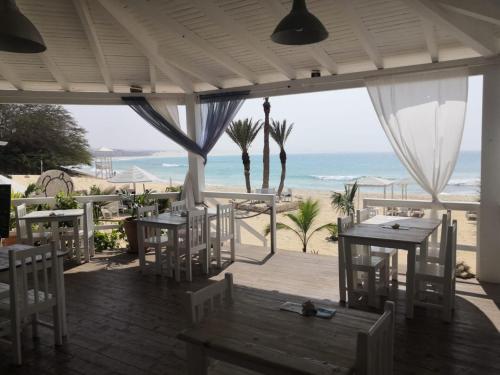 a restaurant with tables and chairs and the beach at Útulný apartmán na Praia de Chaves, Boa Vista in Sal Rei