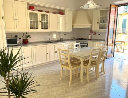 cocina con armarios blancos, mesa y sillas en A Casa di Nonna Anna en Porto Azzurro