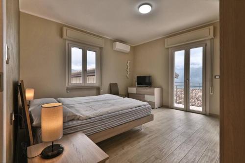 1 dormitorio con 1 cama, TV y ventanas en Appartamento Stella -Rebomaholidays, en Olzano