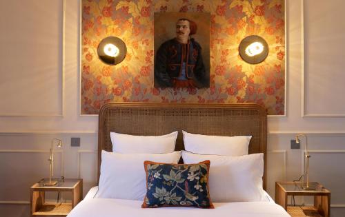 a bedroom with a bed with a portrait of a man on the wall at Hôtel Bristol Pau in Pau