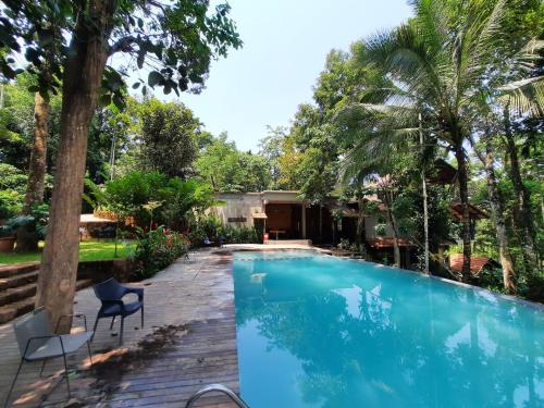 una piscina con 2 sillas y una casa en Willow Resorts, en Ambalavayal