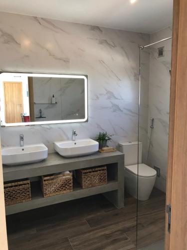 a bathroom with two sinks and a mirror and a toilet at A Beira Do Vale, Carvoeiro in Carvoeiro