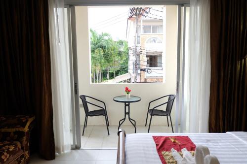 a bedroom with a table and chairs and a window at Sea Boss Homestay in Kata Beach
