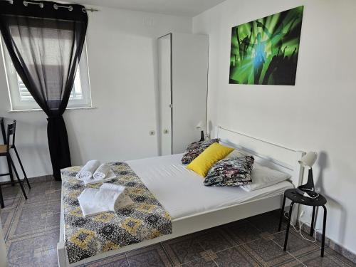 1 dormitorio con cama blanca y almohadas amarillas en Apartments ANTONIA - S. Novalja, en Stara Novalja