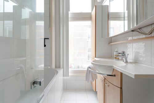 een witte badkamer met een wastafel en een douche bij Zandvoort Zenith - Beautiful Apartment in Zandvoort
