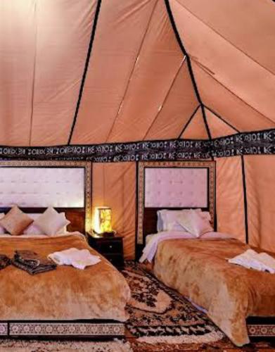 um quarto com 2 camas numa tenda em Luxury Local Camp em Merzouga