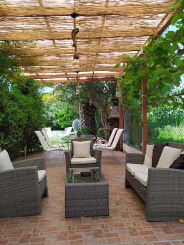 un patio con muebles de mimbre y pérgola de madera en Studios Periklis en Limenas