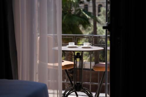 una mesa con dos tazas en el balcón en All Seasons Boutique Hotel - Jerusalem, en Jerusalén