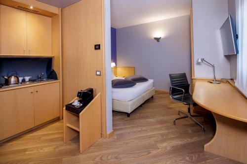 a small room with a bed and a desk and a table at Best Western Plus Executive Hotel and Suites in Turin