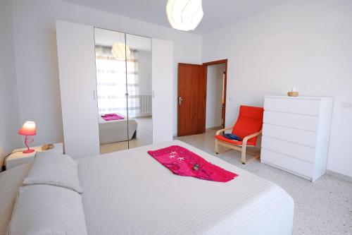 ein weißes Schlafzimmer mit einem Bett und einem Stuhl in der Unterkunft Appartamento Bellariva B1-MyHo Casa in Porto San Giorgio