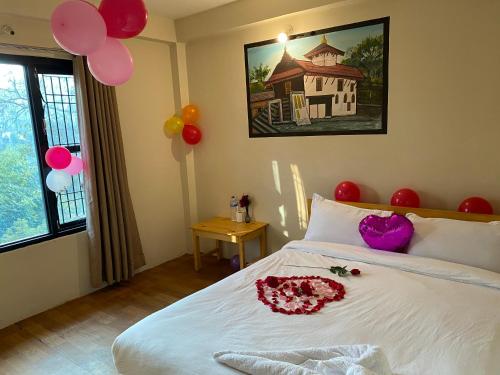 a bedroom with a white bed with balloons on the wall at Hotel Aagaman - Best Family Hotel in Bandipur in Bandīpur