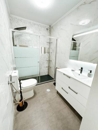 a white bathroom with a toilet and a sink at Golden Place-Costa da Caparica in Costa da Caparica