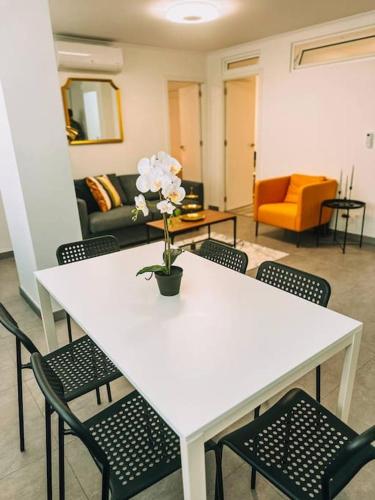 a white table with chairs and a vase with flowers on it at Golden Place-Costa da Caparica in Costa da Caparica