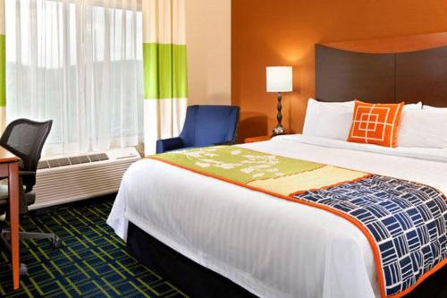 a hotel room with a large bed and a desk and chair at Fairfield Inn & Suites Tulsa South Medical District in Tulsa