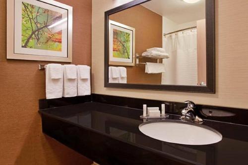 a bathroom with a sink and a mirror and towels at Fairfield Inn & Suites Tulsa South Medical District in Tulsa