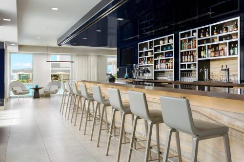 a bar with white chairs in a restaurant at AC Hotel by Marriott San Juan Condado in San Juan