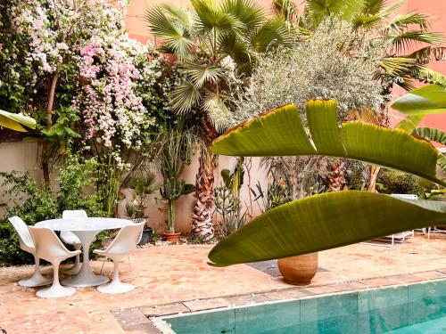 un patio con mesa, sillas y plantas en L'Annexe-Villa patio arboré & piscine privée, en Marrakech