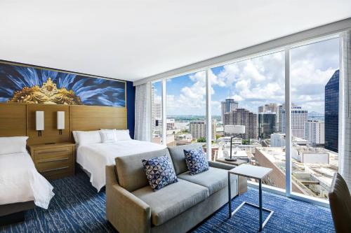 ニューオーリンズにあるResidence Inn by Marriott New Orleans French Quarter Area/Cen Bのベッド1台、ソファ、大きな窓が備わるホテルルームです。