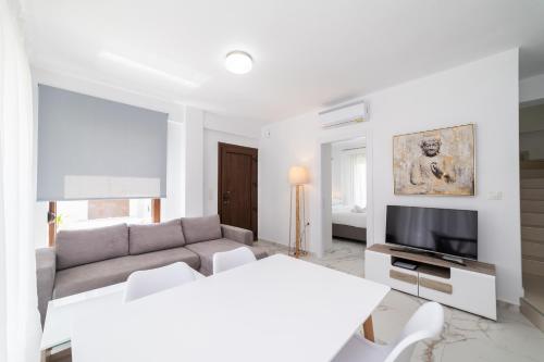 sala de estar blanca con sofá y TV en Argilos Residential Complex en Ofrínion