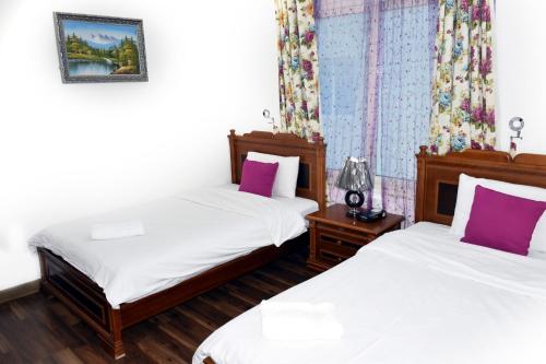 a bedroom with two beds with white and purple pillows at Arinza Tower Quality Apartments in Kuwait