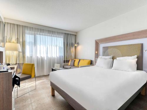 - un grand lit blanc dans une chambre d'hôtel dans l'établissement Novotel Paris Nord Expo Aulnay, à Aulnay-sous-Bois