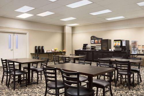 a cafeteria with tables and chairs and a kitchen at Days Inn & Suites by Wyndham Sault Ste. Marie ON in Sault Ste. Marie