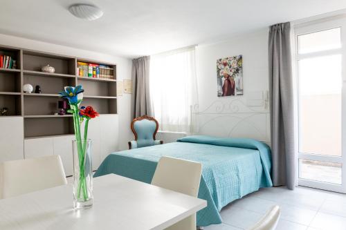 CAMPI ALTI AL MARE APARTMENTS في فولونيكا: غرفة نوم بسرير وطاولة مع ورود في مزهرية