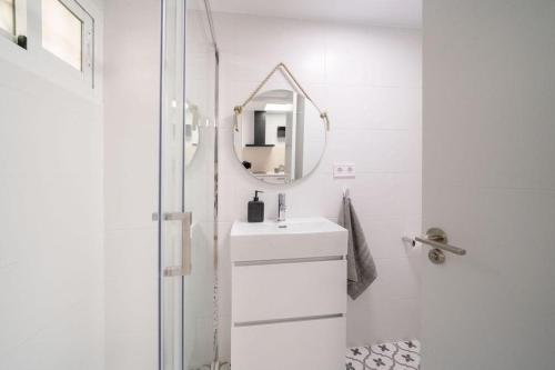 ein weißes Badezimmer mit einem Waschbecken und einem Spiegel in der Unterkunft Benalmadena Jupiter Sunsea View Apartments in Benalmádena