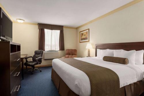 a hotel room with a large bed and a desk at Days Inn & Suites by Wyndham Sault Ste. Marie ON in Sault Ste. Marie