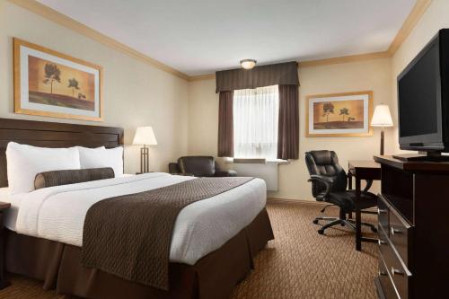 a hotel room with a bed and a flat screen tv at Days Inn & Suites by Wyndham Sault Ste. Marie ON in Sault Ste. Marie