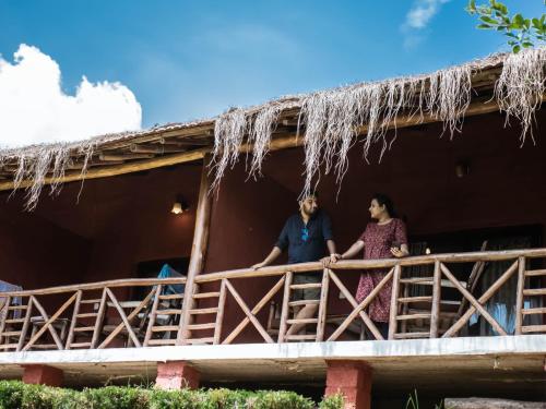 a man and woman standing on a porch of a house at Deshadan Eco Valley Resort - An Eco friendly Mud House in Kanthalloor