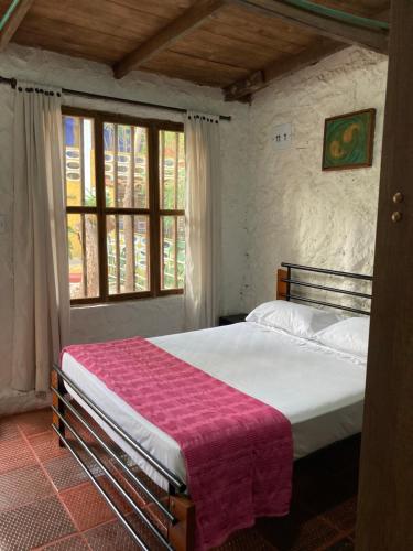 a bedroom with a bed with a pink blanket on it at Villa Margarita in Puerto Colombia