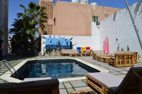 a pool in a patio with chairs and a building at Rafiki Hostel in Wadi Musa